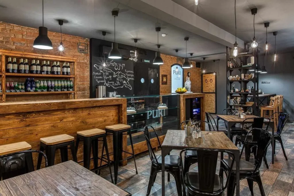 High-ceiling loft cafe with exposed air ducts and large windows.