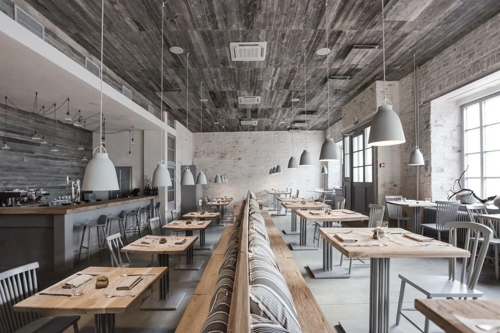 Open-plan cafe design with concrete flooring and minimalist wooden furniture.