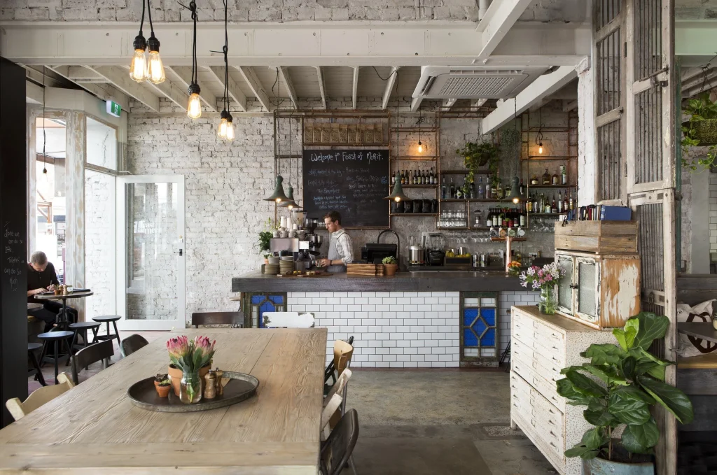 Small coffee shop layout with a dark metal service counter and bar stools.